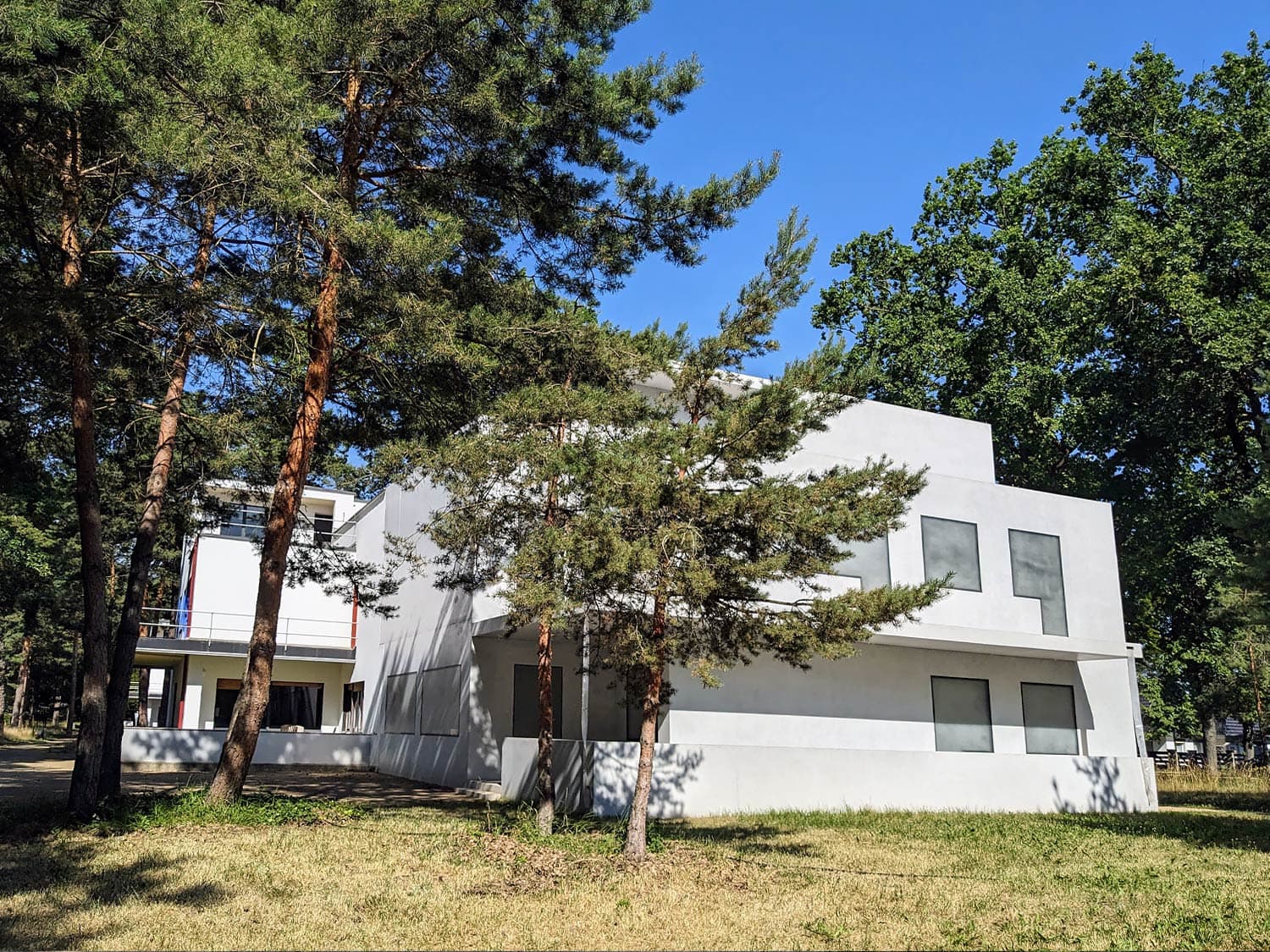 Foto der bekannten Meisterhäuser, die in einem kleinen Wäldchen nahe Dessau stehen, aufgenommen bei blauem Himmel