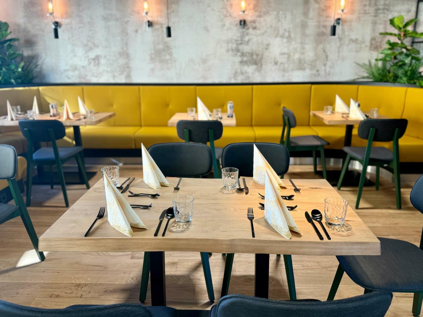 Foto von einem gedeckten Massivholztisch für sechs Personen in einem Restaurant bei Dessau, im Hintergrund sieht man weitere Tische