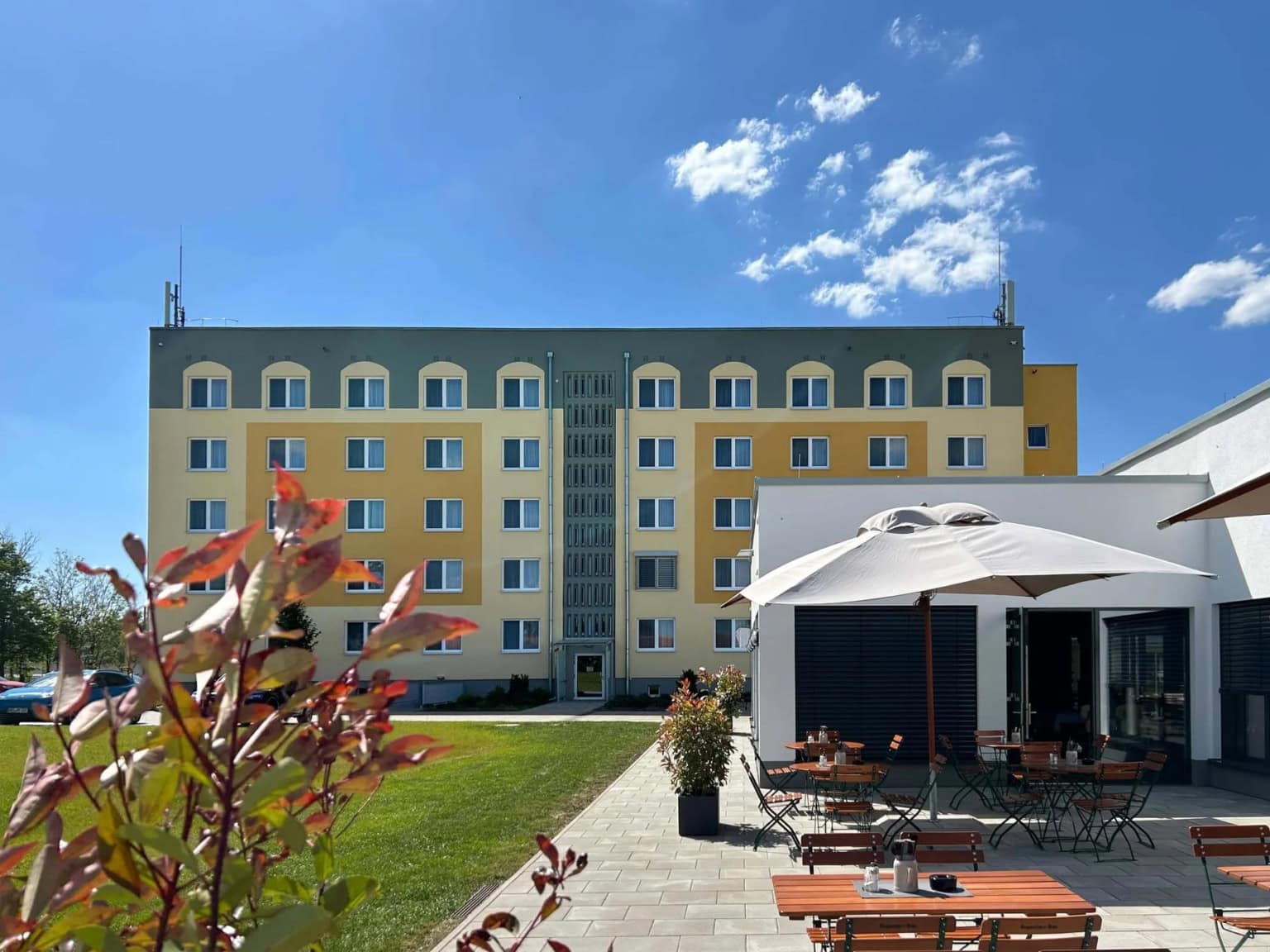 Aufnahme vom Außenbereich des Restaurant Elbebrücke mit Tischen, Stühlen und Schirmen, im Hintergrund sieht man das Hotelgebäude