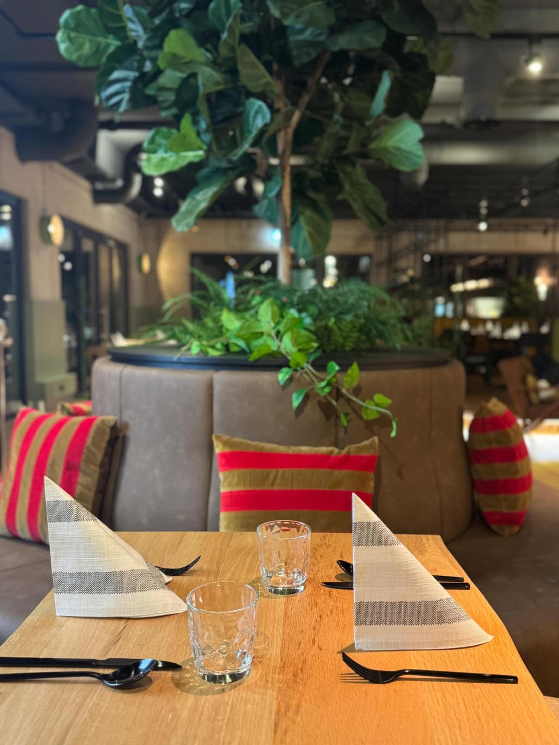 Genütliche Nahaufnahme eines Tischs vor einer Rundbank mit buntem Polsterkissen