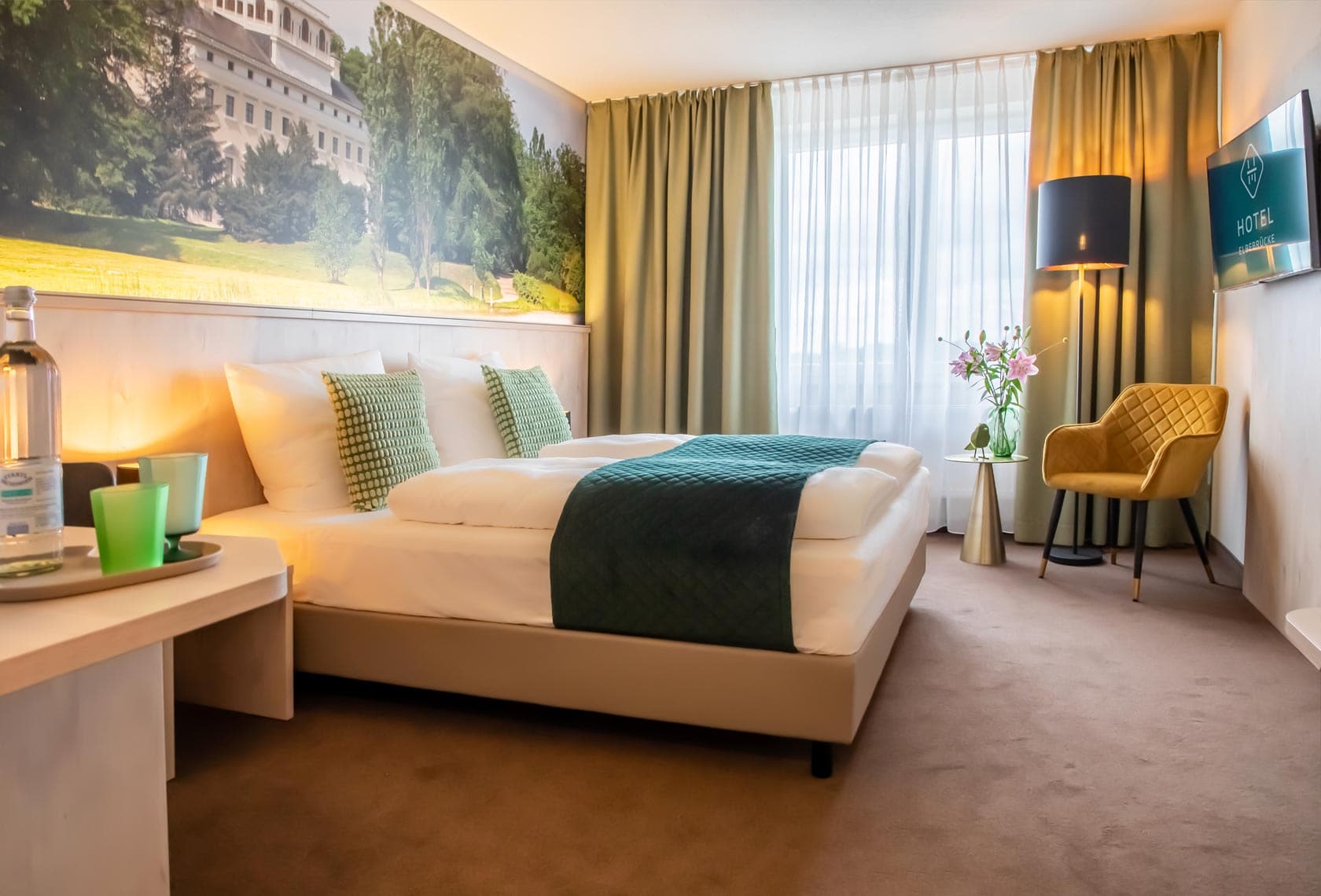 Aufnahme eines barrierefreien Hotelzimmers mit bequemen Doppelbett, TV und angrenzendem Badezimmer im Hotel Elbebrücke