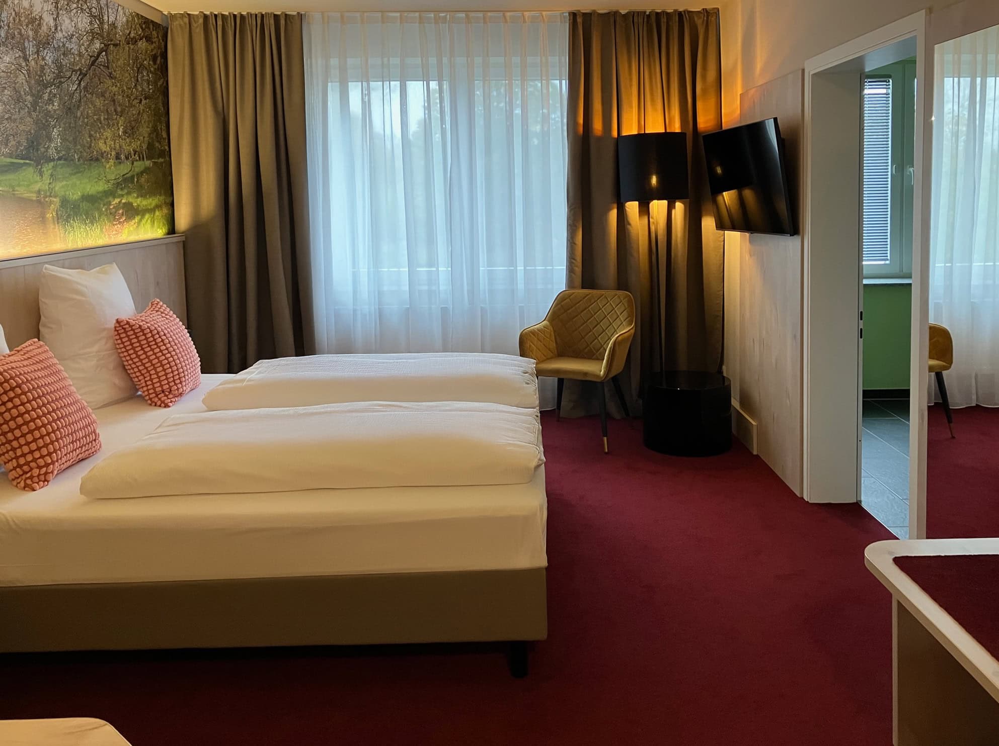 Aufnahme eines barrierefreien Hotelzimmers mit bequemen Doppelbett, TV und angrenzendem Badezimmer im Hotel Elbebrücke