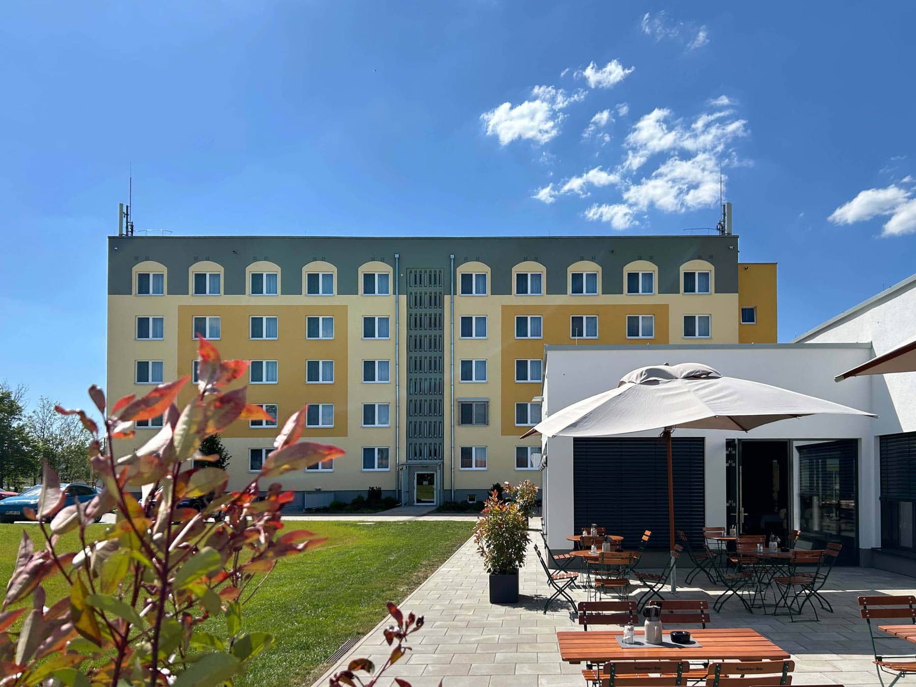 Aufnahme vom Außenbereich des Restaurant Elbebrücke mit Tischen, Stühlen und Schirmen, im Hintergrund sieht man das Hotelgebäude